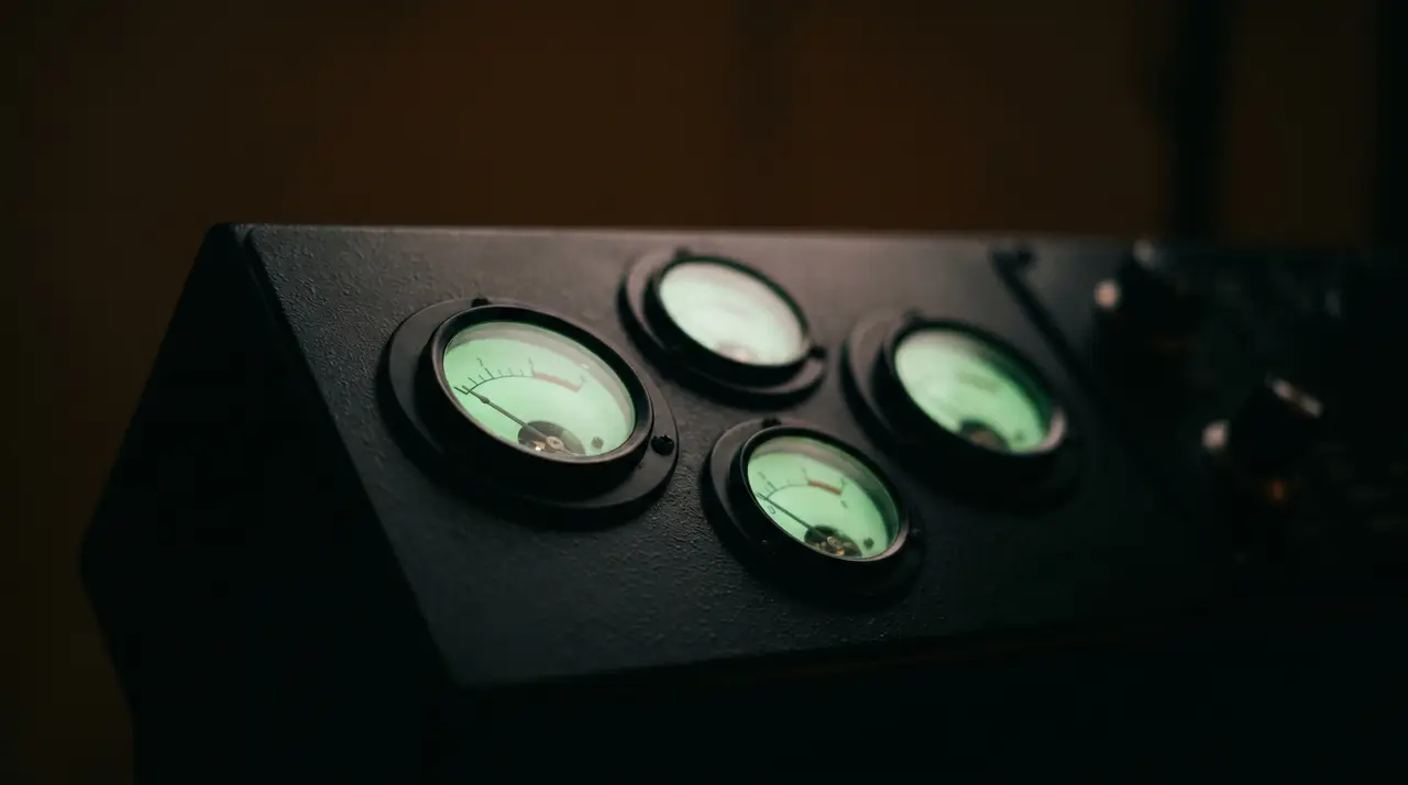 four small green dials on a dark panel, one needle low and steady